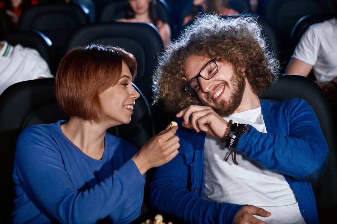 Roześmiana para studentów je popcorn w sali kinowej